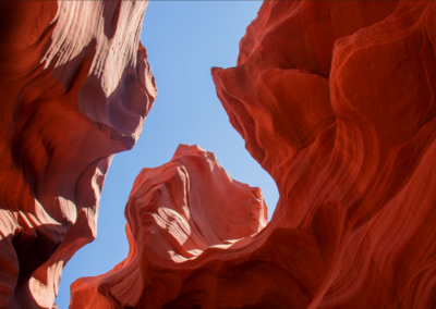 Views of red sandstone walls lit by beams of sunlight filtering through the narrow openings above.
