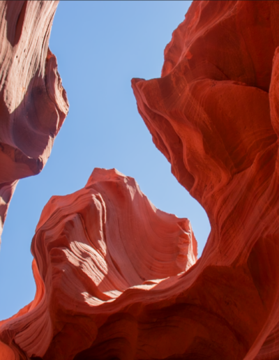 Views of red sandstone walls lit by beams of sunlight filtering through the narrow openings above.